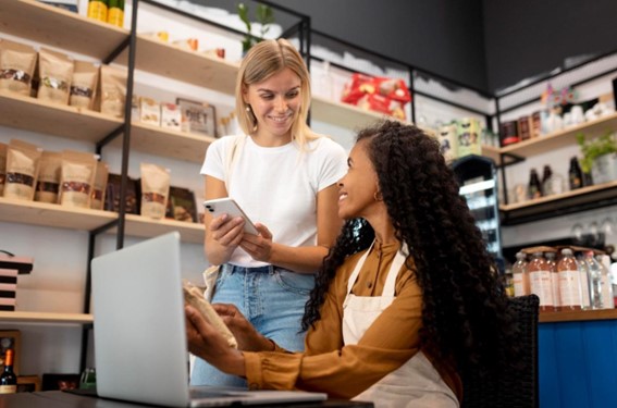 Duas mulheres em uma loja representando um pequeno negócio e com computador usando ferramenta no-code.